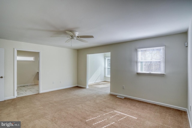 carpeted empty room with baseboards, visible vents, and ceiling fan