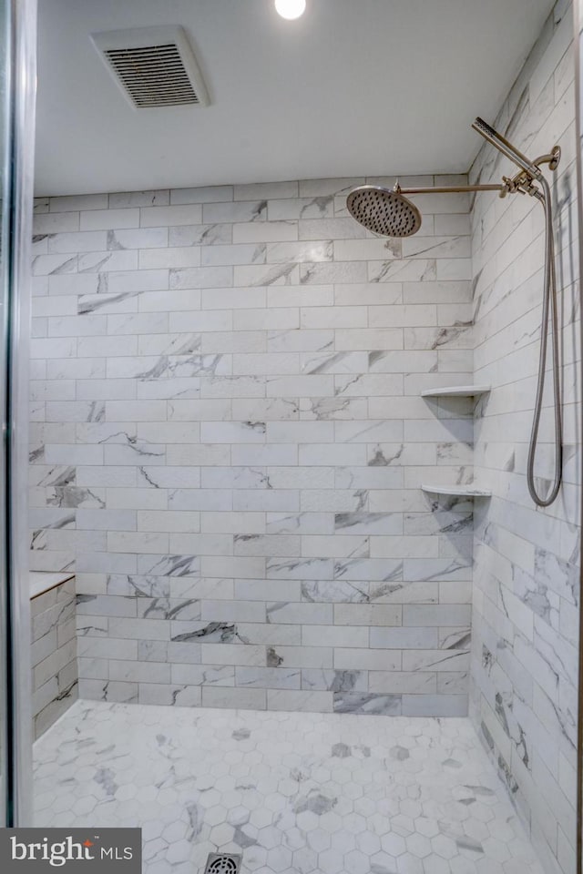 full bath with visible vents and a tile shower