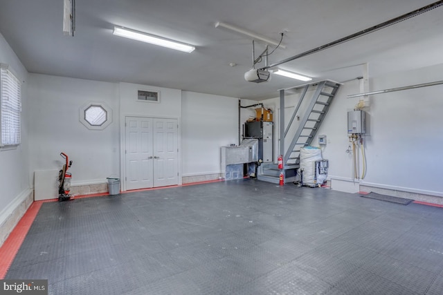 garage featuring baseboards, tankless water heater, visible vents, and a garage door opener