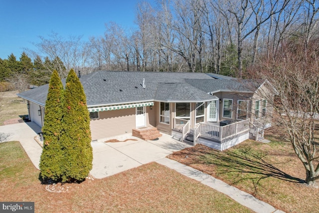 ranch-style house with a shingled roof, a front lawn, and concrete driveway