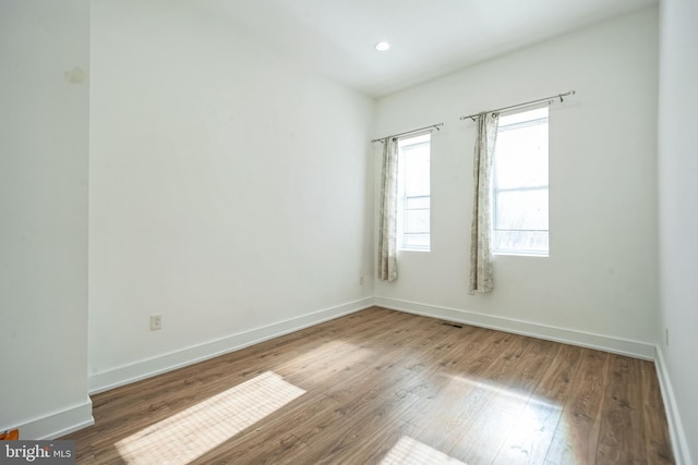 spare room featuring recessed lighting, wood finished floors, and baseboards