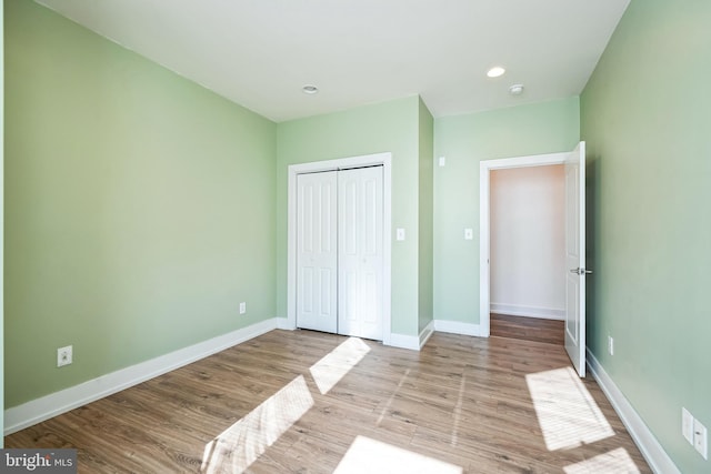 unfurnished bedroom featuring light wood finished floors, a closet, recessed lighting, and baseboards