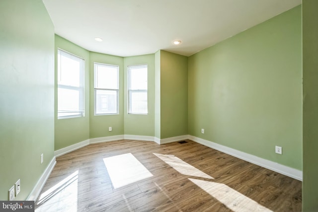 spare room with baseboards and light wood finished floors