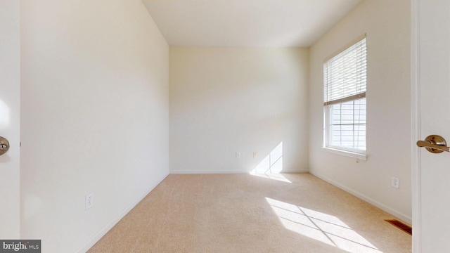 spare room with light carpet, baseboards, and visible vents