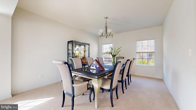 dining space featuring light carpet, a notable chandelier, and baseboards