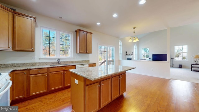 kitchen with white appliances, open floor plan, a center island, pendant lighting, and a sink