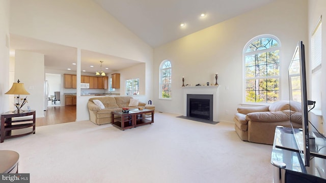 living area featuring high vaulted ceiling, recessed lighting, a fireplace with flush hearth, and light colored carpet