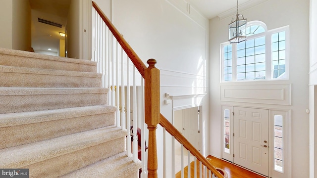 entryway featuring stairs, visible vents, a notable chandelier, and wood finished floors