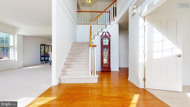 entrance foyer with stairway, wood finished floors, visible vents, and baseboards