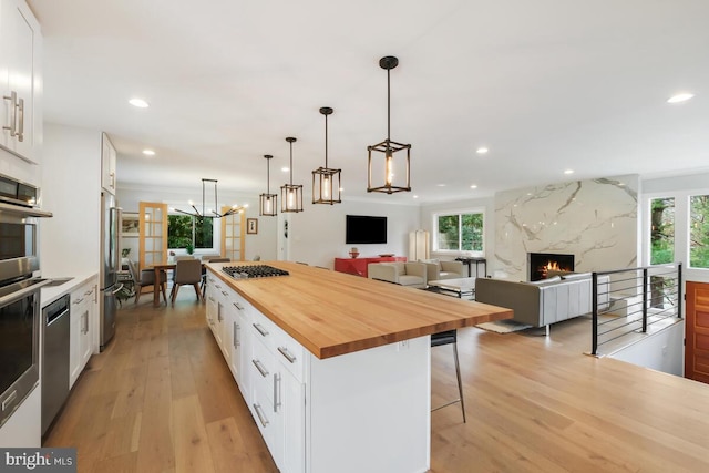 kitchen with butcher block countertops, white cabinets, a breakfast bar, and a healthy amount of sunlight