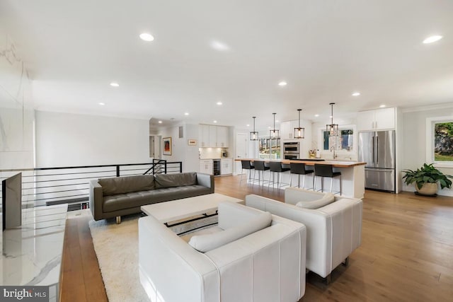 living room featuring recessed lighting, light wood-type flooring, and ornamental molding