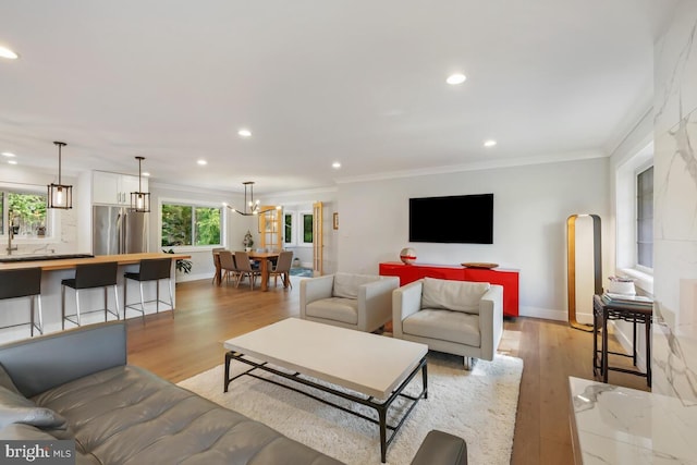 living room featuring crown molding, light wood-style flooring, and baseboards