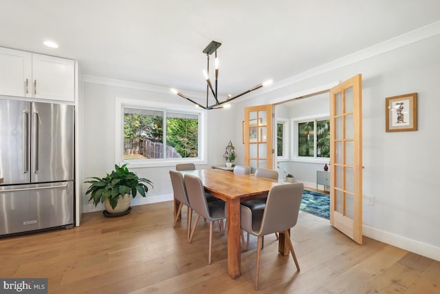 dining area with a notable chandelier, french doors, light wood-style floors, and plenty of natural light