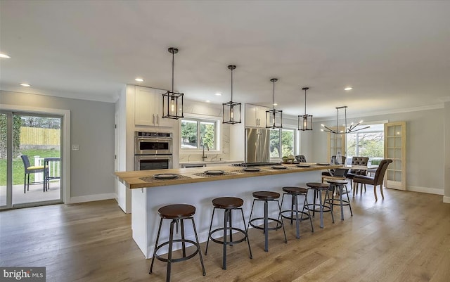 kitchen with a kitchen bar, butcher block countertops, light wood-style flooring, and white cabinetry