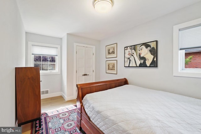 bedroom with visible vents, baseboards, and wood finished floors