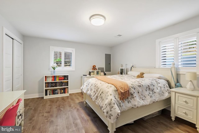 bedroom featuring multiple windows, baseboards, and wood finished floors