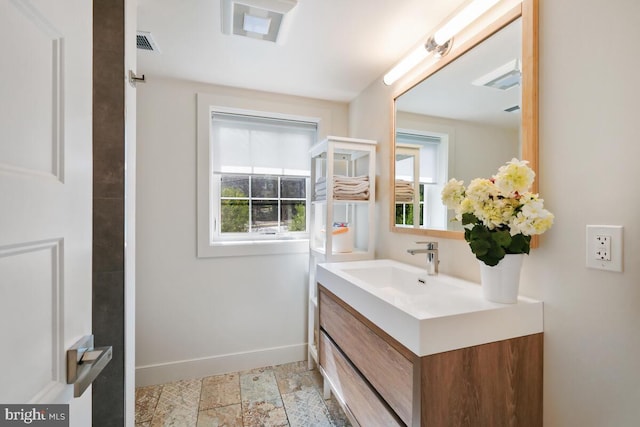 bathroom with visible vents, baseboards, vanity, and stone finish floor