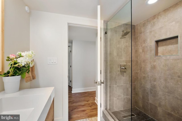 full bathroom featuring wood finished floors, baseboards, and tiled shower