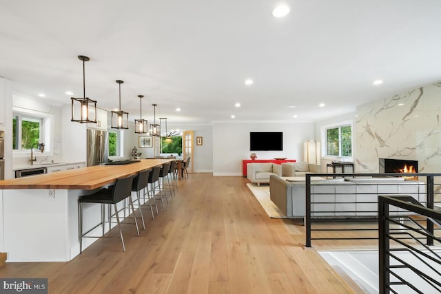 interior space with recessed lighting, baseboards, light wood-style floors, and a high end fireplace