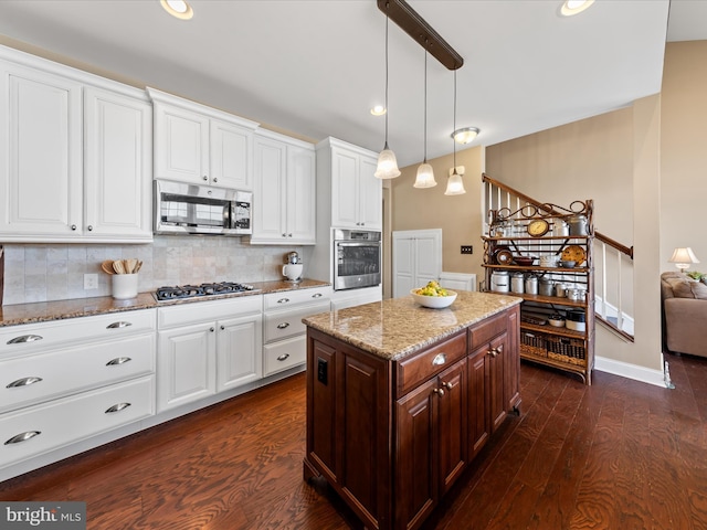 kitchen featuring backsplash, dark wood finished floors, appliances with stainless steel finishes, white cabinets, and light stone countertops