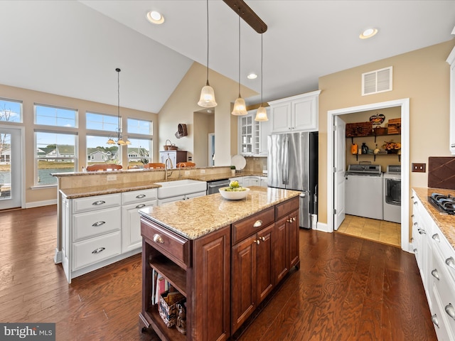 kitchen with visible vents, a sink, washing machine and dryer, stainless steel appliances, and a peninsula