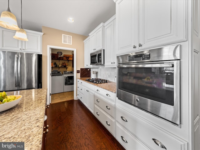kitchen with visible vents, stainless steel appliances, white cabinets, washer and dryer, and tasteful backsplash