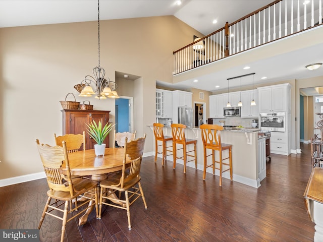 dining space with dark wood finished floors, an inviting chandelier, baseboards, and high vaulted ceiling