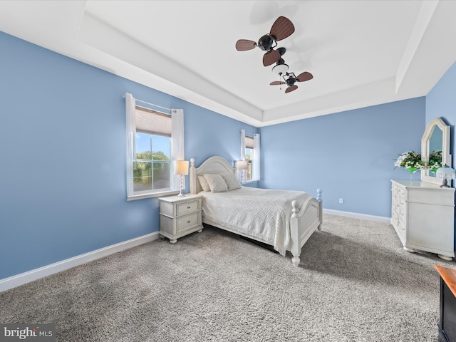 bedroom with carpet flooring, a ceiling fan, a tray ceiling, and baseboards