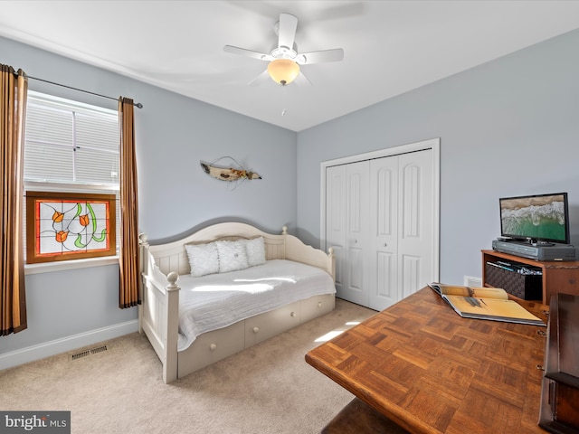 bedroom with visible vents, baseboards, light carpet, a closet, and a ceiling fan