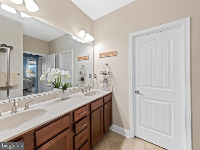 full bathroom featuring a sink, baseboards, double vanity, and tile patterned flooring