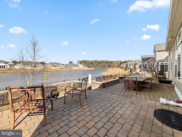 view of patio / terrace with a residential view, a water view, and outdoor dining space