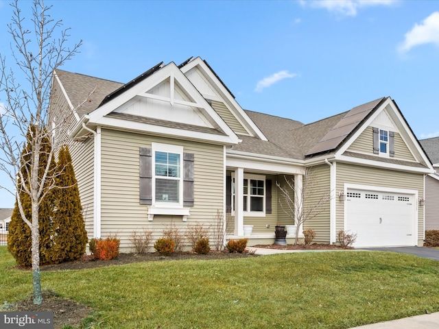 craftsman house with driveway, a shingled roof, and a front yard