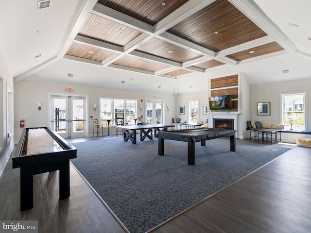 rec room featuring beamed ceiling, visible vents, a warm lit fireplace, wood finished floors, and french doors