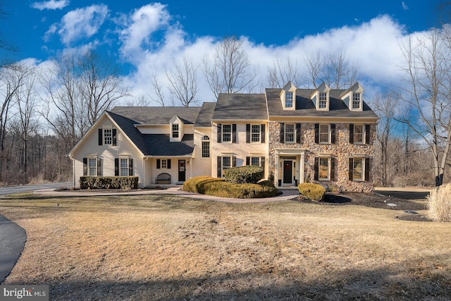 colonial home featuring stone siding and a front lawn