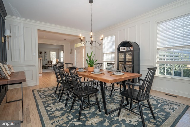 dining space featuring ornamental molding, a healthy amount of sunlight, visible vents, and a decorative wall