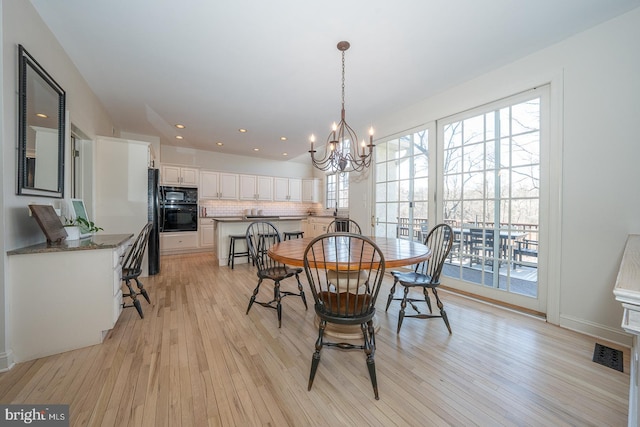 dining space with light wood-style floors, recessed lighting, visible vents, and an inviting chandelier