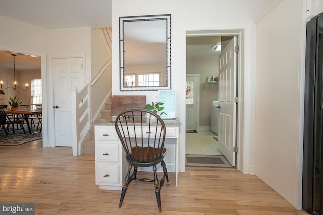 interior space featuring a chandelier, washer / clothes dryer, stairs, and light wood-style floors