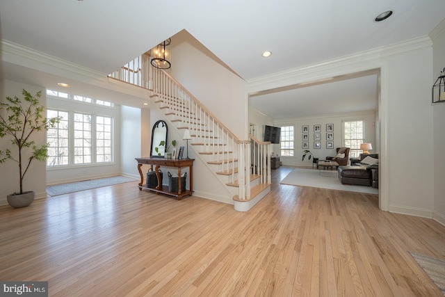 foyer with ornamental molding, hardwood / wood-style flooring, and stairs