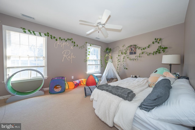 carpeted bedroom featuring a ceiling fan, visible vents, and baseboards