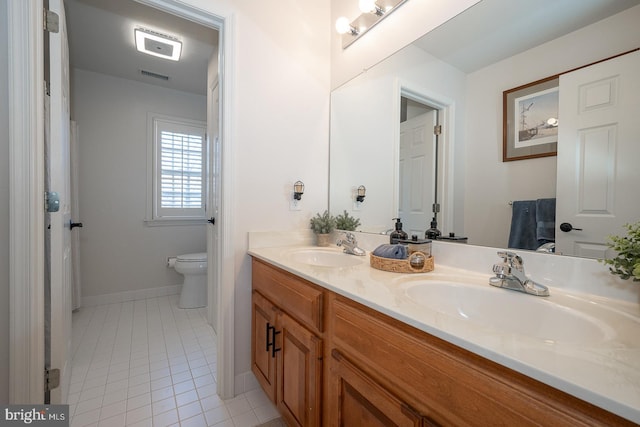 full bath with toilet, tile patterned flooring, double vanity, and a sink