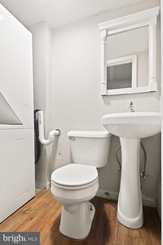 half bathroom featuring wood finished floors, toilet, and baseboards