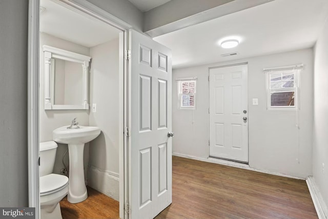 half bathroom with baseboards, visible vents, toilet, and wood finished floors