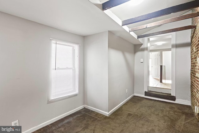 interior space featuring dark colored carpet, lofted ceiling with beams, and baseboards