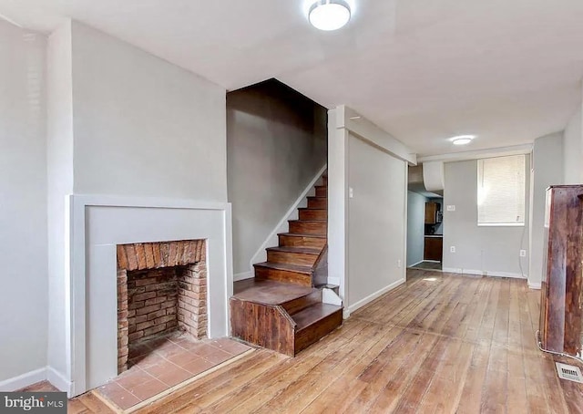 interior space with wood-type flooring, a fireplace, visible vents, and baseboards