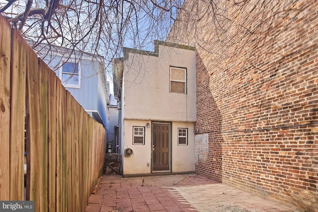 rear view of property featuring a patio, fence, and stucco siding