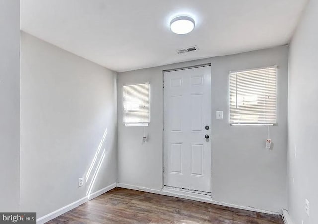 foyer entrance featuring dark wood-type flooring, visible vents, plenty of natural light, and baseboards