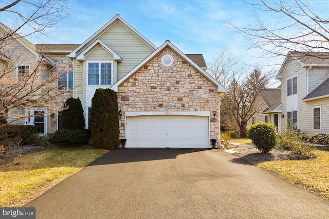 traditional-style home with driveway, stone siding, and an attached garage