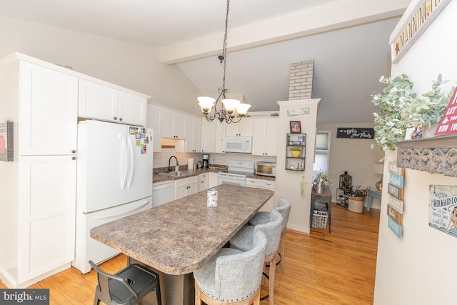 kitchen with white appliances, a kitchen bar, white cabinetry, and a sink