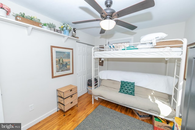 bedroom featuring a closet, ceiling fan, baseboards, and wood finished floors