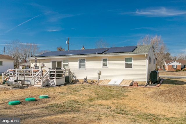 back of house featuring a yard, roof mounted solar panels, heating fuel, and central air condition unit